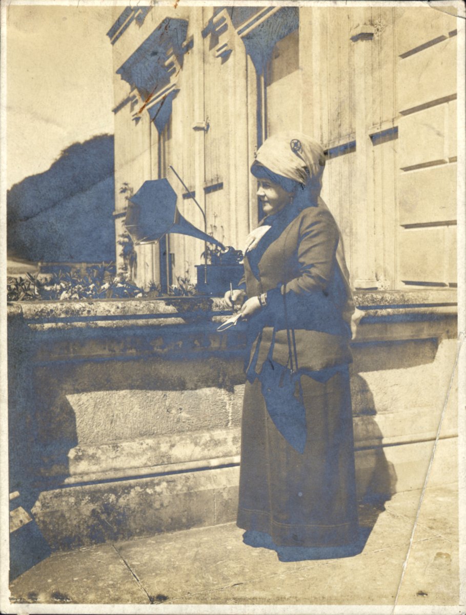Charlotte Milligan Fox (1864-1916) at the front door of Curraghmore House, Co. Waterford, listening to a recording of a fiddler; thx @QUBLibrary omeka.qub.ac.uk/items/show/574 More on her collecting activities via @ITMADublin itma.ie/texts/fox/#clo… #herstory #bailitheoiríban