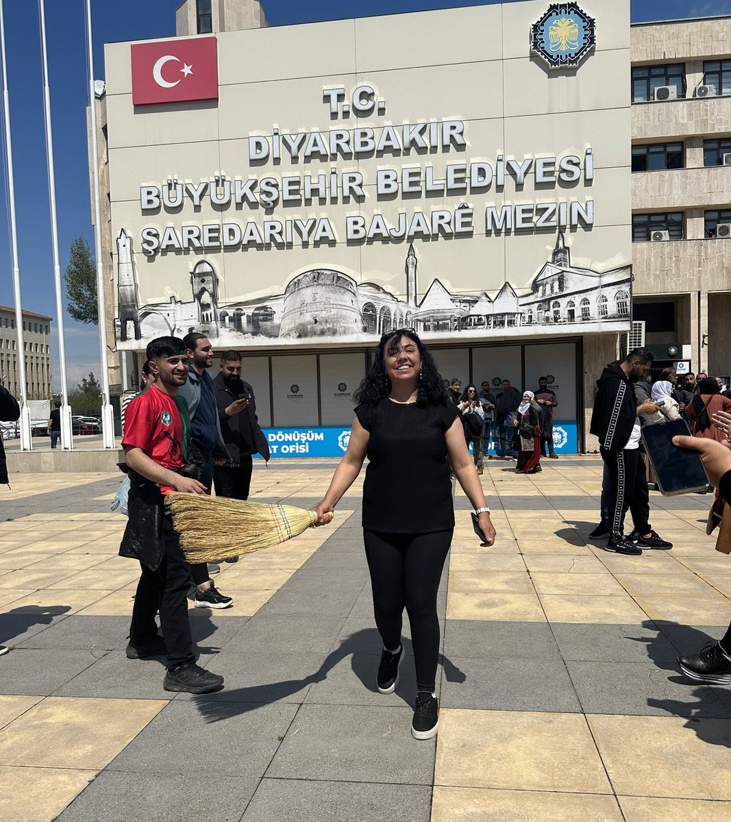 DEM Parti eş başkanların Diyarbakır Büyükşehir Belediyesine girişinden sonra bir kadın elindeki süpürgeyle belediye binasının önünü süpürdü.
