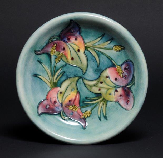 #MoorcroftMonday 'Arum Lily' Plate by Walter Moorcroft, designed in the late 1950s A ceramic plate decorated with a blue-green ground. There are three lillies in tube-lined decoration, coloured with pinks, yellows and greens. cannon-hall.com/collections