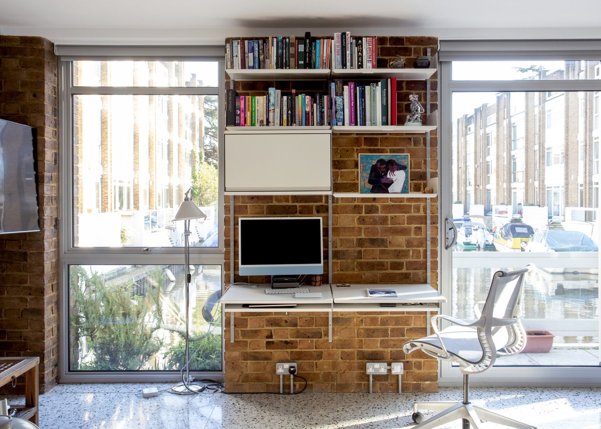 Bricks and water A two-bay 606 system with twin desk-shelves, eye-level cabinet and shelves, wall-mounted onto exposed brickwork and set between a pair of water-side windows—all combining to create an idyllic workspace in Richmond-upon-Thames, England. vitsoe.com/606