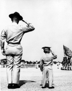 Sgt. Myron Chambers and his son, 2 and half year-old 'colonel' Marvin Chambers, salute the colors during recruit graduation ceremonies for the 304 series, on 8 April 1965.