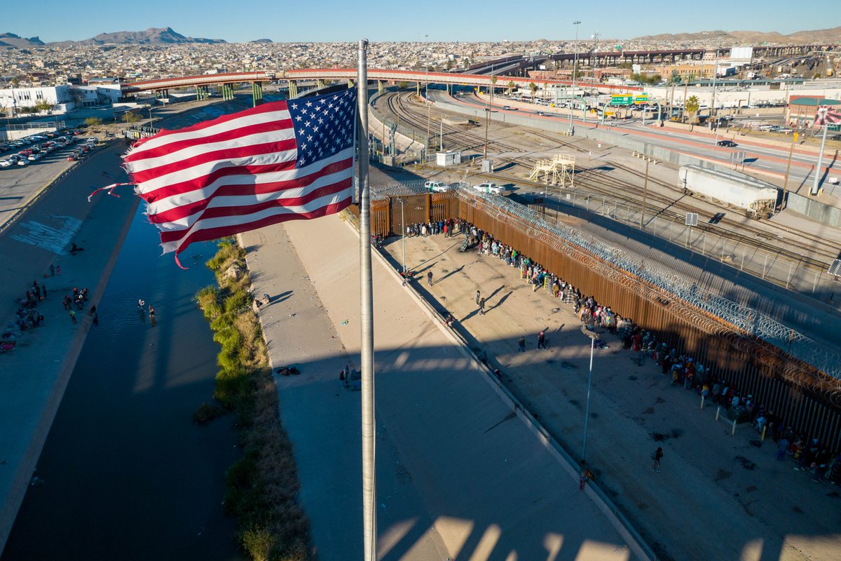 U.S. flag flying over an international bridge as aliens line up next to the border fence between the United States of America 🇺🇸 and Mexico 🇲🇽, to seek asylum. 📸: Dec. 22, 2022, in El Paso, Texas. #Riigipiir #Confine #Border #国境 #边界 #Granica #Grenze #Fronteira #Frontera
