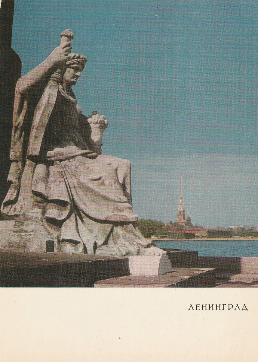 Female figure at the base of one of the Rostral columns overlooking the Peter and Paul fortress. Leningrad. Photo postcard by B. Raskin (1969).