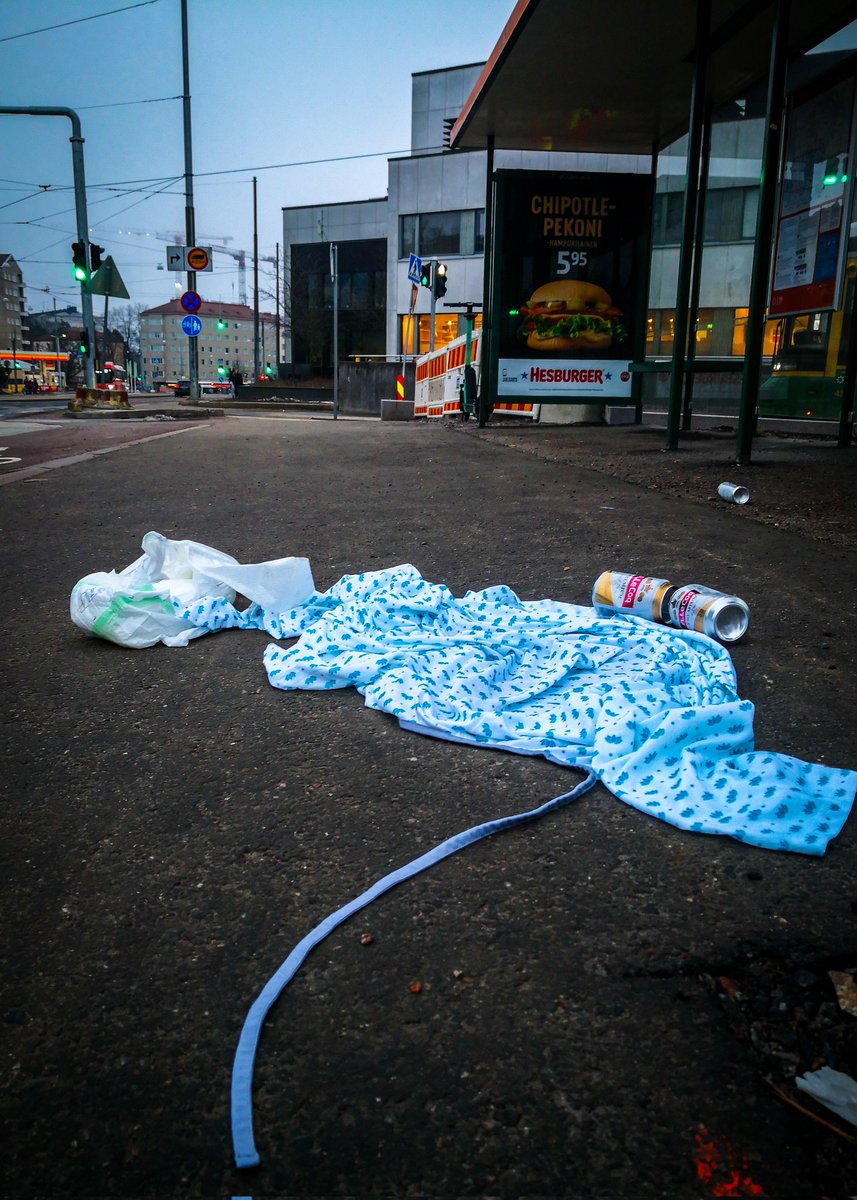 Tämän asetelman taustalla on varmasti oma tarinansa. Ja sen tarinan haluaisin kuulla.

Teippivaippa, avopaita ja kaljatölkkejä sairaalan läheisellä bussipysäkillä