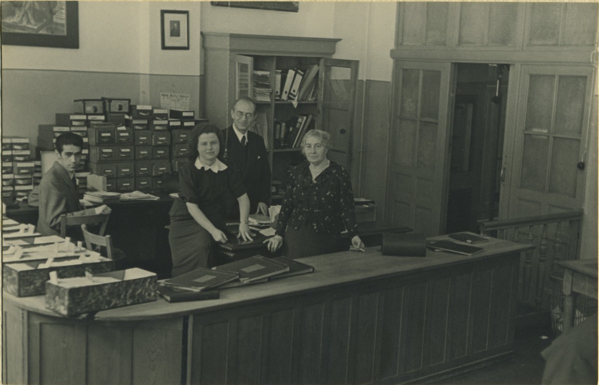 This #NationalLibraryWeek we honor librarians who defied Nazis. Jenny Wilde smuggled Jewish books to safety. Pictured are Jenny Wilde (R), Adele Sperling (2nd from L), & two unidentified colleagues in the library of the Hochschule für die Wissenschaft des Judentums. 📷@lbinyc