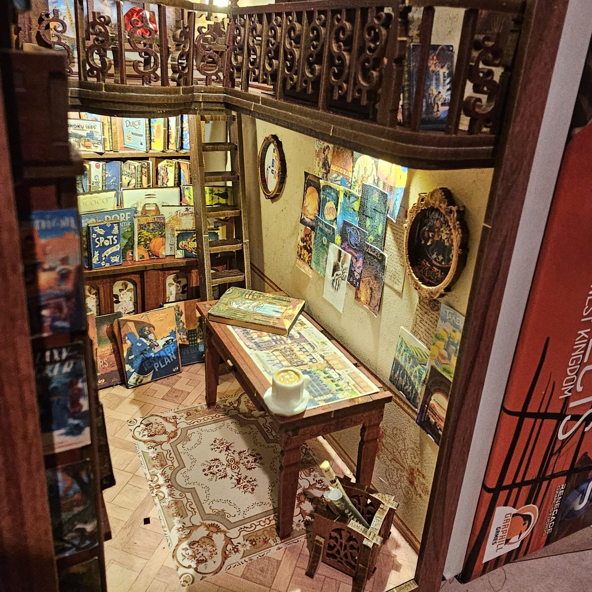 time_of_corvid's tweet photo. I made not a book nook but a boardgame nook, tucked gently between @garphillgames boxes. Weather Machine by @vitallacerda and @ianotooletweets is on the table but I'd NEVER put a cup of tea on it in real life. https://t.co/r88IlvXr9w