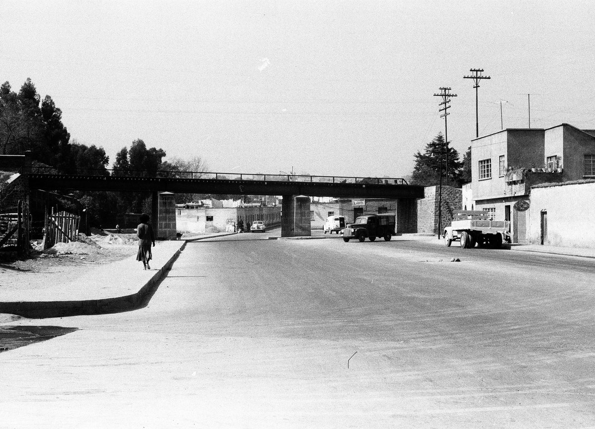 La avenida Molinos y el antiguo puente del ferrocarril a Cuernavaca, hoy el Periférico, en la década de 1950. Al frente está la esquina con Leonardo da Vinci, en Mixcoac. 📷: Colección de Francisco Montellano