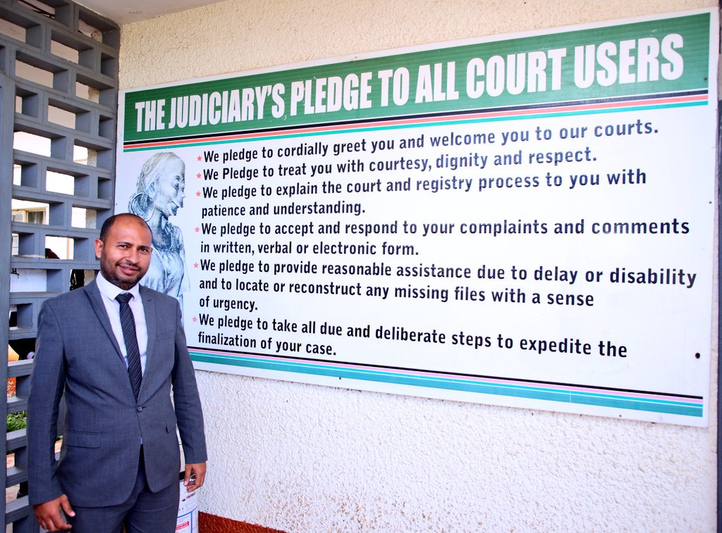 Standing beside the Judiciary pledges displayed at the entrance of Meru Law Courts, a powerful reminder of our commitment to justice and fairness for all court users.