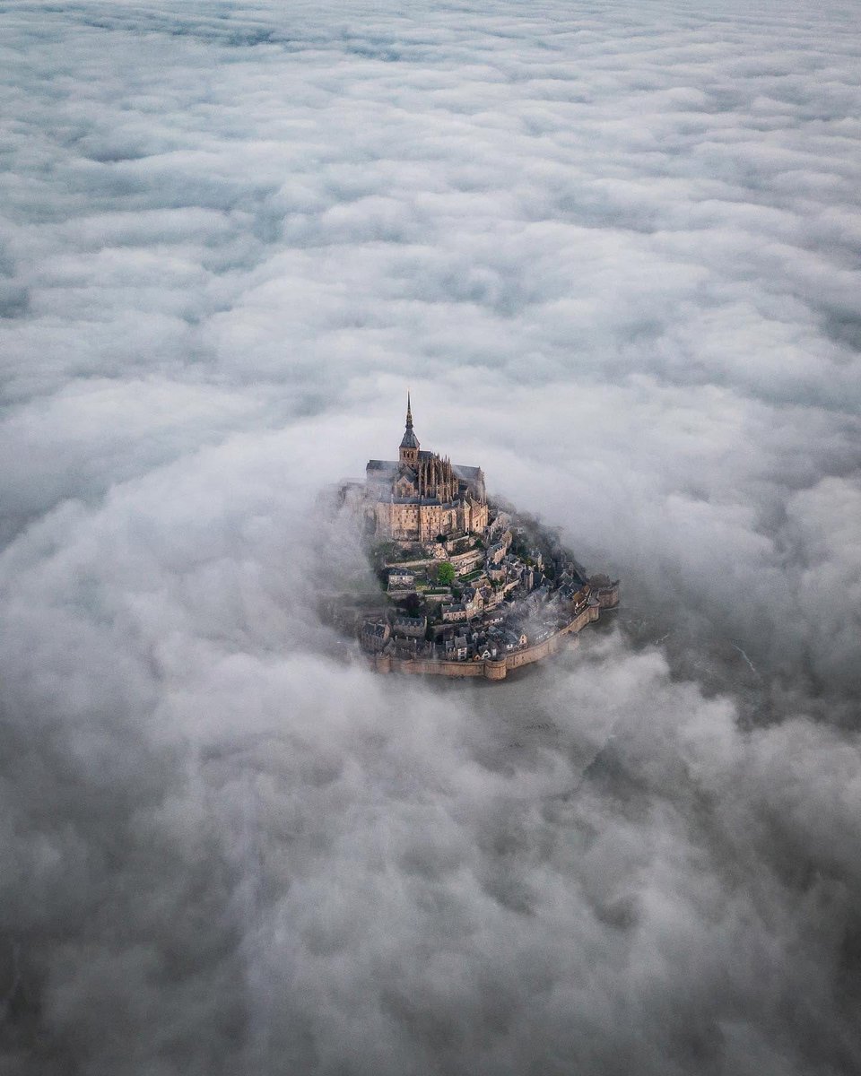 Emerging from the mists: Mont Saint-Michel 🇫🇷✨ Behold the ethereal beauty of this ancient island fortress, as it appears to float among the clouds ☁️🏰 📷: Ewout Pahud