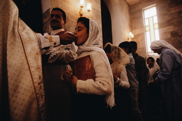 A girl receives communion during a Palm Sunday service in Baghdad’s St. George Church. Baghdad, Iraq. 1999. 📷: Michael S. Yamashita