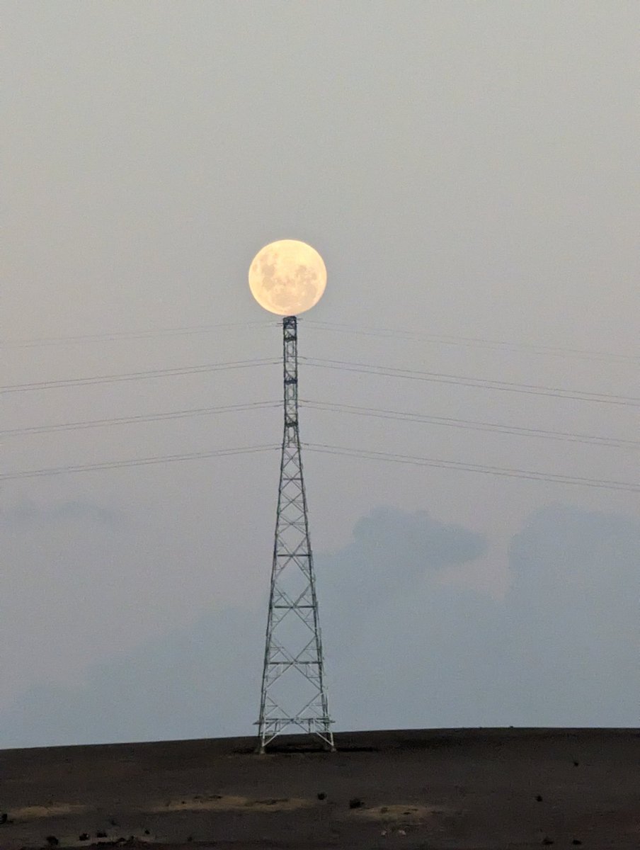 Sometimes the moon rises too early and so it rests on-top of the electricity towers. It waits for the sun to set before carrying on its journey over the night sky.