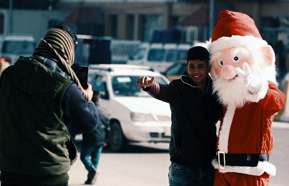 A man dressed in a Santa Claus outfit hands souvenir, in the Shiite holy city of Najaf, Iraq, 2015.

📷: Haidar Hamdani