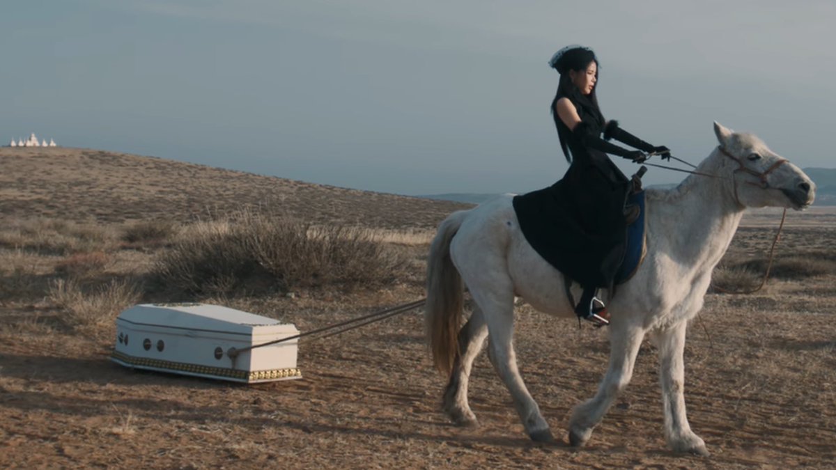 solar of mamamoo riding an horse in a funeral gown while dragging a coffin