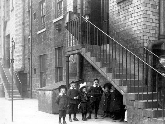 A photograph of number 67-143 Saltmarket in Glasgow. With the Rear of tenements, showing group of children posed, taken circa 1902