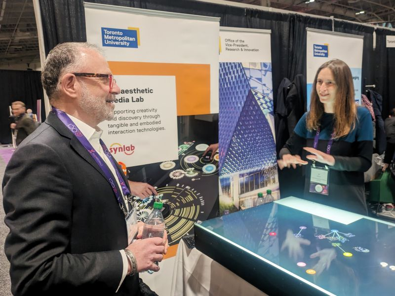 Synlab Director Prof. Ali Mazalek presenting her research at the Ontario Centre of Innovation's DiscoveryX conference in Toronto.
<a href="/RTA_tmu/">RTA School of Media at The Creative School</a> <a href="/TMU_GrantsTeam/">TMU Grants Team</a> <a href="/researchTMU/">Research – Toronto Metropolitan University</a> <a href="/TMUgraduate/">TMU Graduate and Postdoctoral Studies</a> <a href="/A__Sultana/">Afroza Sultana, PhD</a> <a href="/OCInnovation/">Ontario Centre of Innovation (OCI)</a> #DiscoveryX2024