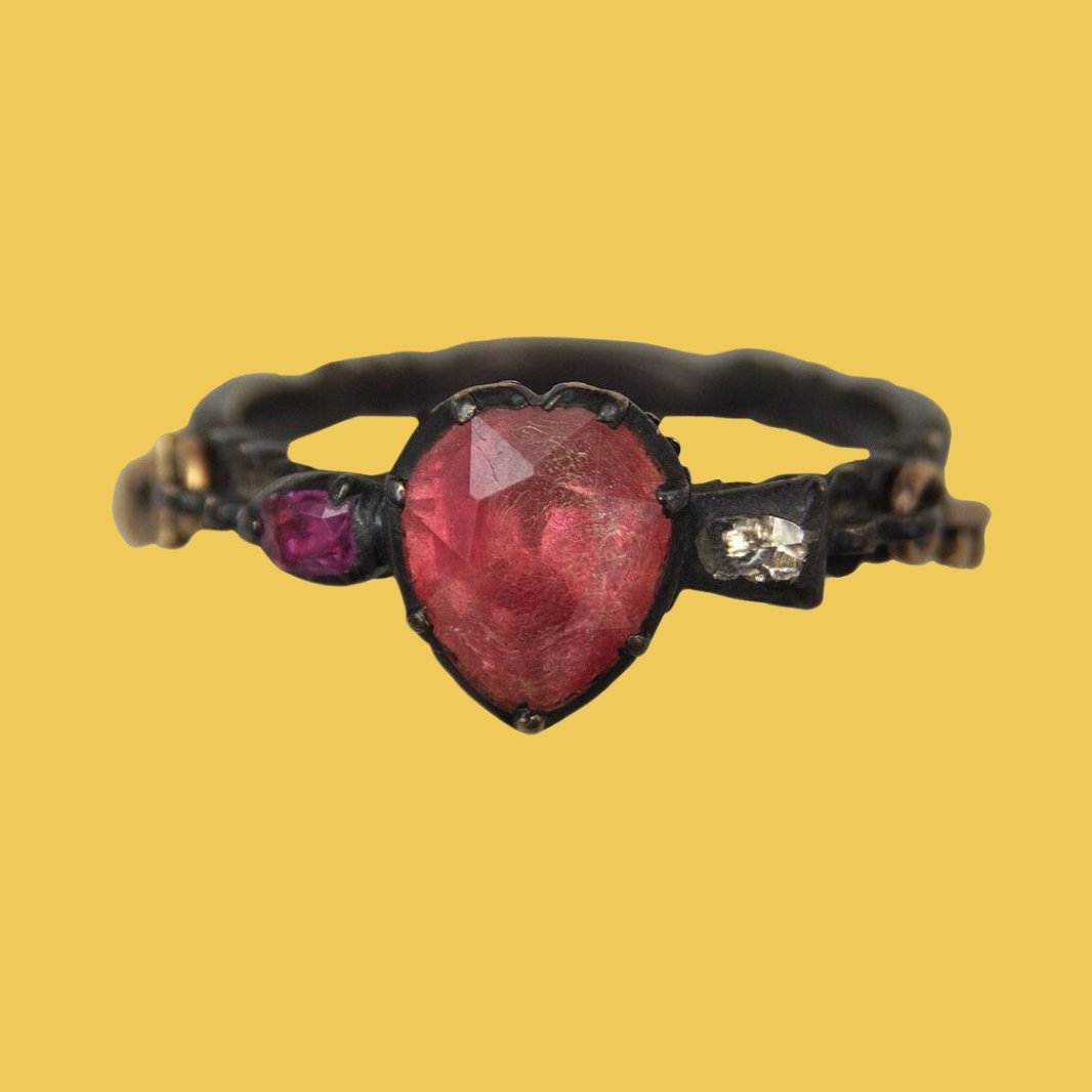 This children's ring token is replete with symbols of love, including... ❤️ a little ruby heart 🔒 a tiny padlock which was a symbol of care in the 18th century 🖋️ an inscription in French that translates to ‘he who neglects me loses me’