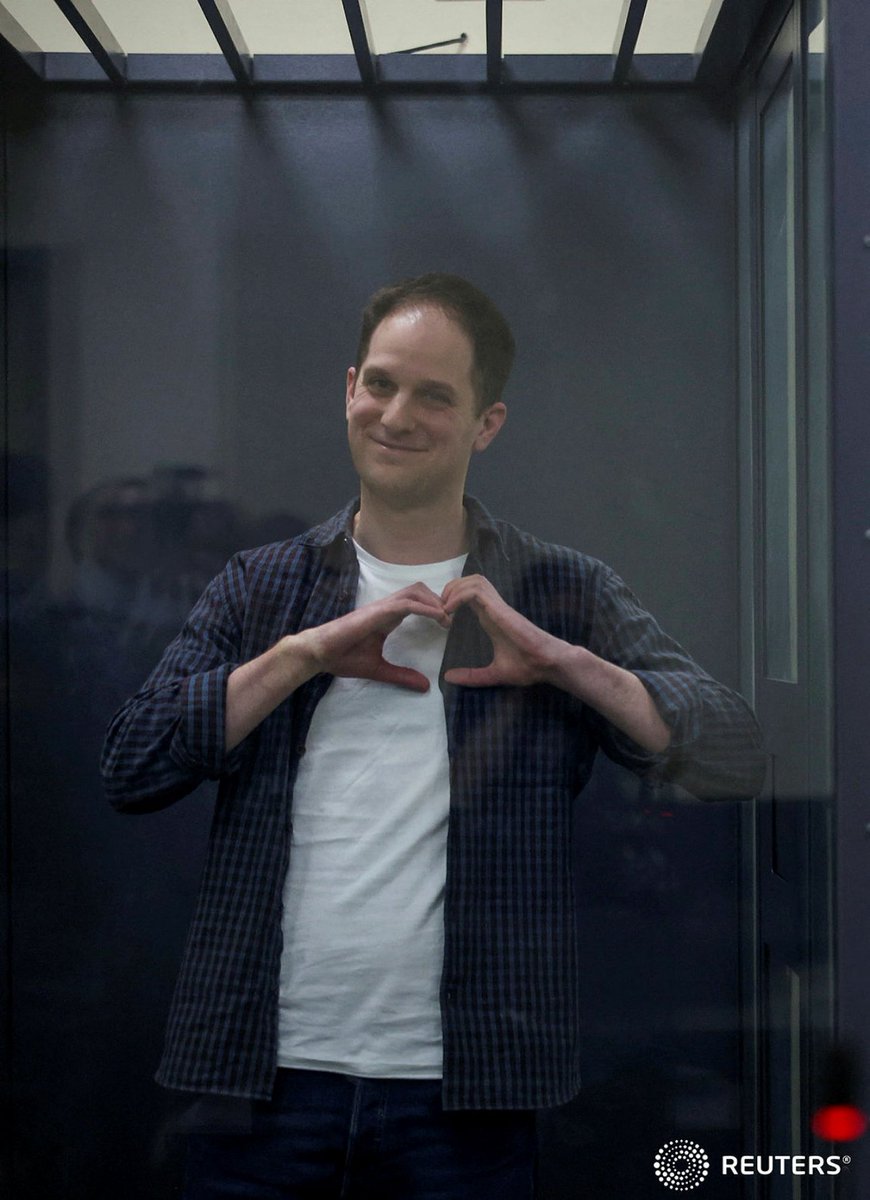 Wall Street Journal reporter Evan Gershkovich, who is in custody on espionage charges, makes a heart-shaped gesture behind a glass wall of an enclosure for defendants as he attends a court hearing in Moscow, Russia, April 23, 2024. REUTERS/Tatyana Makeyeva