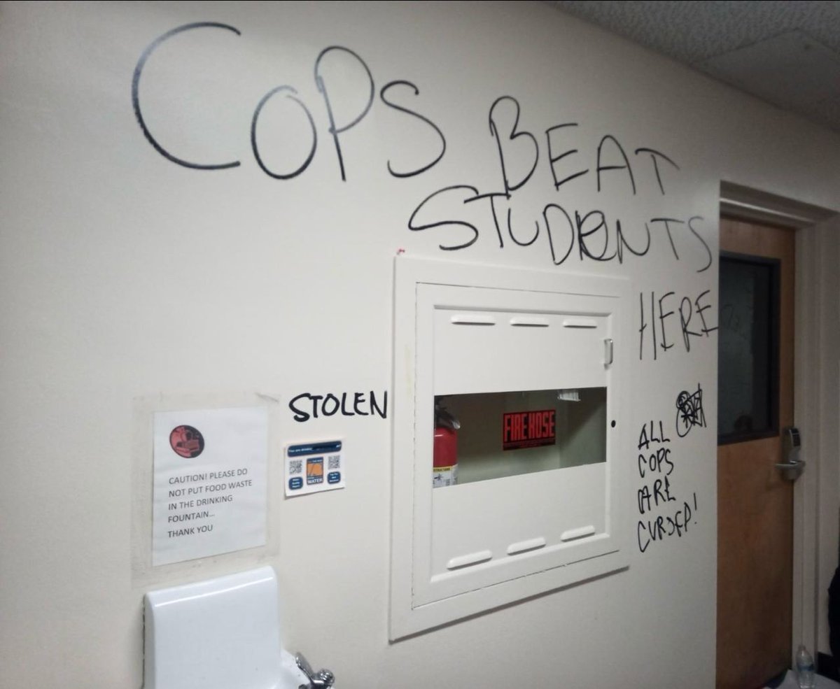 'Graffiti from inside Siemens Hall at Cal Poly Humboldt right now, reading 'Cops beat students here—all cops are cursed.'