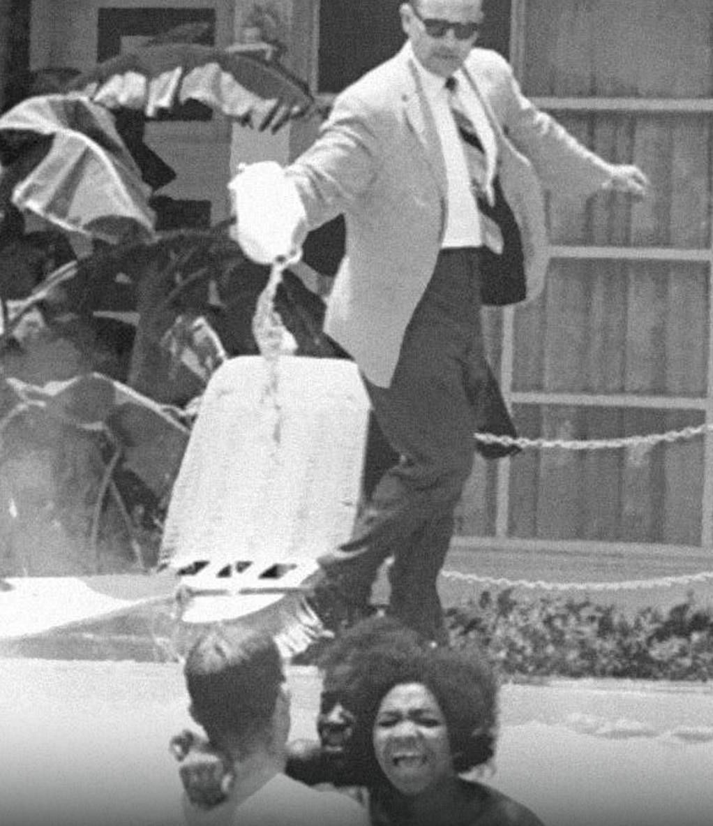 A hotel owner pours acid into a pool of black people. 1964