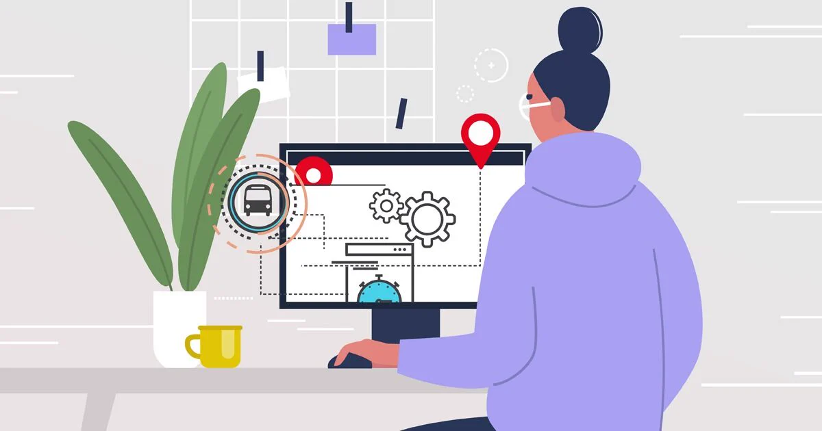 Person sitting at a computer wearing a purple hoodie. The computer screen has gears, wayfinding and OC Transpo O logo. A green plant and yellow mug are next to the screen.  