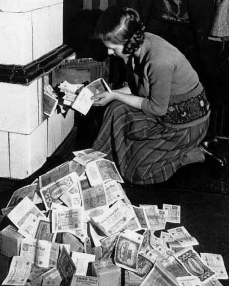 A woman uses banknotes to light her stove during hyperinflation in the Weimar Republic (Germany). Circa 1923