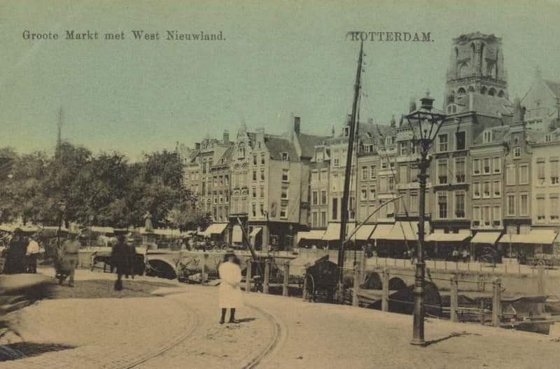 Grotemarkt uit het zuidoosten gezien, in het midden tussen de panden de Wijde Marktsteeg, links de overwelving onder de Grotemarkt en het standbeeld van Erasmus. Boven de panden aan de noordzijde de toren van de Grote Kerk. 1900-1908