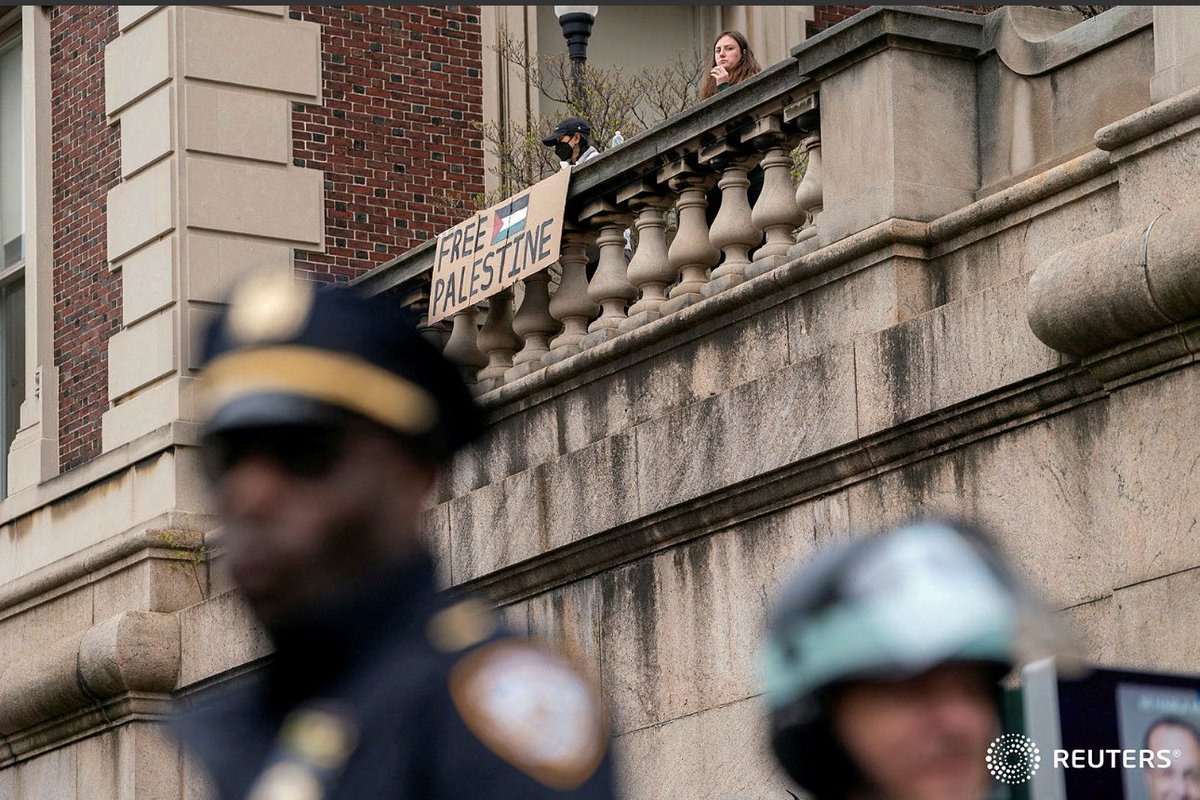 Police stand guard in the foreground as protesters show support for Palestinians in Gaza, at Columbia University in New York City, U.S., April 24, 2024. REUTERS/David 'Dee' Delgado