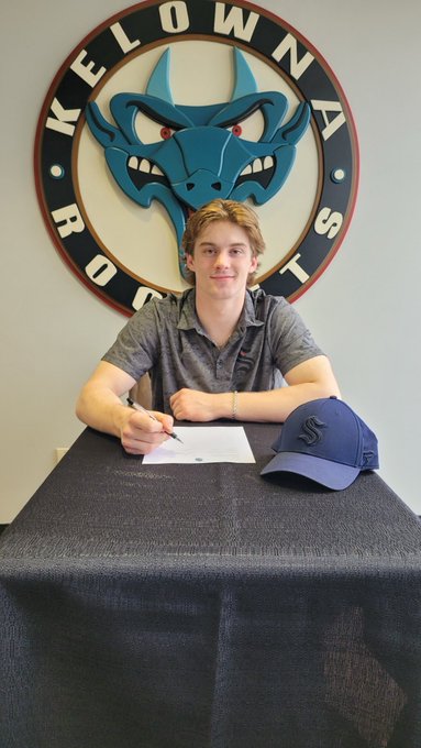 Caden signing contract a table with a kraken hat