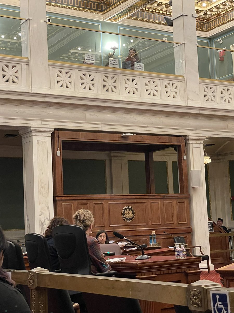 Folks in the balcony hold up signs that read “Say no to Parker’s drug war” every time speakers call out the city’s dangerous return to failed policies from the war on drugs.