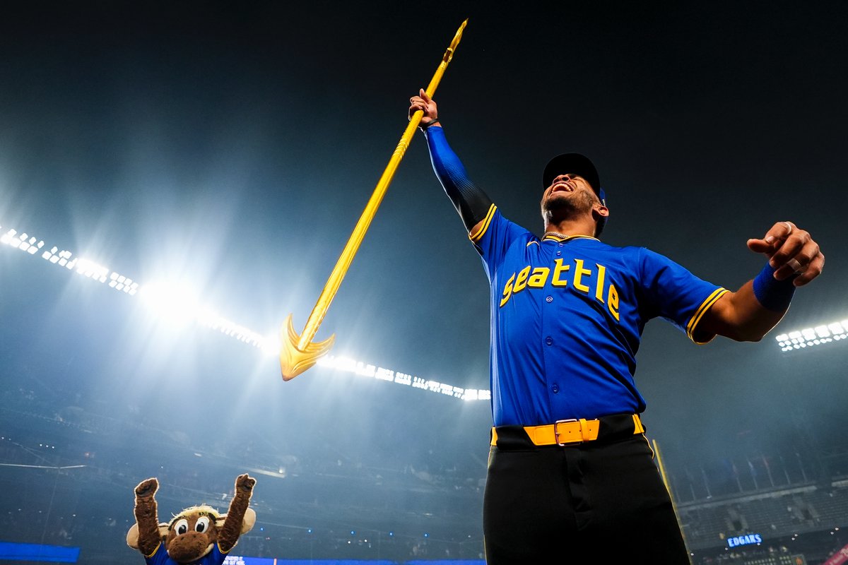 Seattle #Mariners' Julio Rodríguez lifts a trident as the Mariner Moose celebrates behind him after a 4-2 win over the Chicago #Cubs. (AP/Lindsey Wasson)