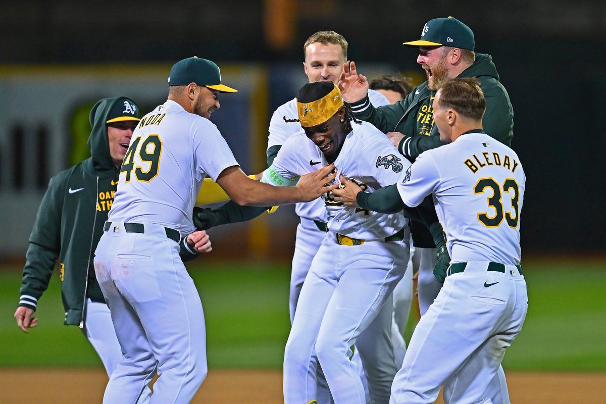Oakland Athletics' Lawrence Butler (4) is mobbed by his teammates after hitting a game winning walk-off single in the 10th inning of their MLB game at the Coliseum in Oakland, Calif., on Friday, April 12, 2024. #rootedinoakland