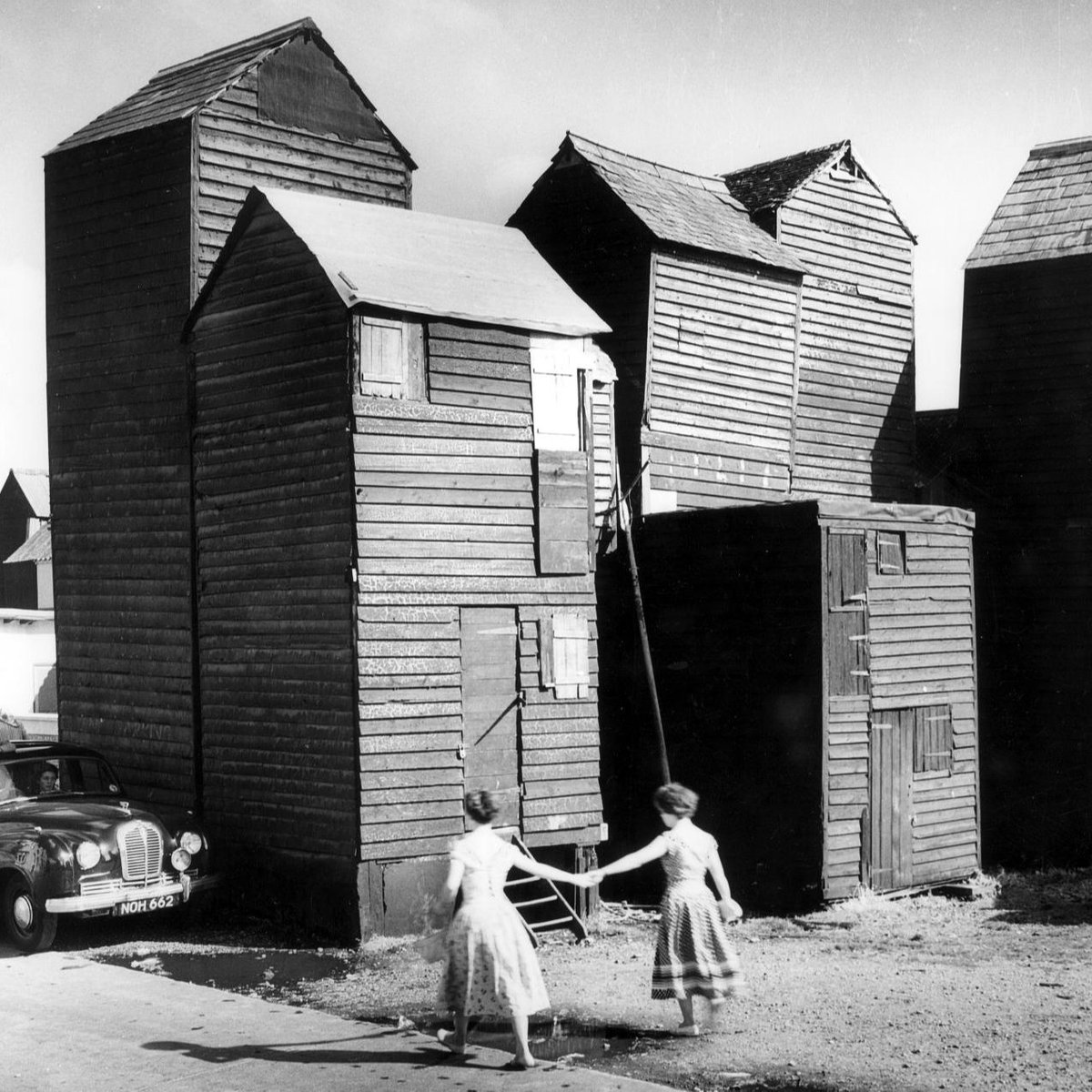 2 women journey to the net and tackle stores in Hastings, East Sussex, in 1956. 📸 The unusually narrow structures were dictated by a restricted plot agreed upon in 1846, so the net shops were forced to grow upwards. Today, the stores still stand in 12 rows on the beach. ⛵