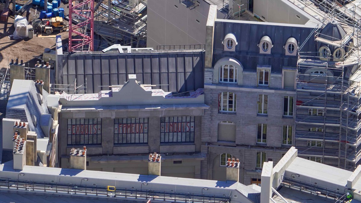 Aerial photo of recently revealed facades in the Harry Potter land at Epic Universe. A slogan is painted in some of the windows.