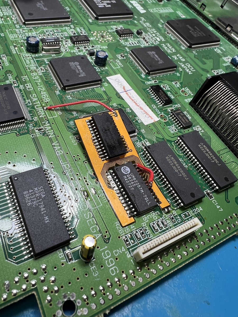 zaxour's tweet photo. It works! This Saturn has top side ram, but that wasn’t a big deal. Just needed some kapton for the shield. 

Process is simple:
Original RAM CS pin 20 goes to original VDD/5V to disable it
FRAM hijacks everything else, flex grounds /OE
Supply 5V https://t.co/LfXS72pJhx