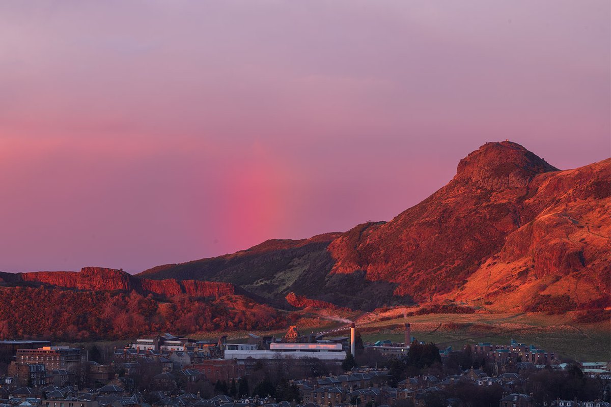 Red rainbow at sunset behind Arthur's Seat as the last sunlight picked out the original St Trinnean's School for Girls which is now St Leonard's Hall & part of the Pollock Halls university estate #Redbow #Edinburgh