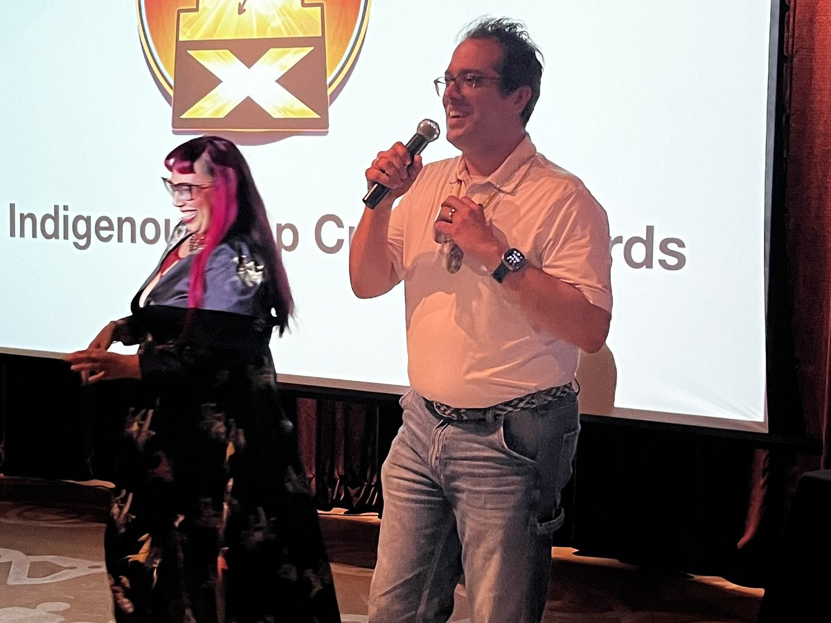 IndigenousCon's tweet photo. #IndigipopX director Kristin Gentry presented Dr. Indiginerd, Lee Francis 4 with a special (surprise) award for his efforts to advance Indiginerdity and Indigenous Pop Culture! https://t.co/MEyZk3T2Gz