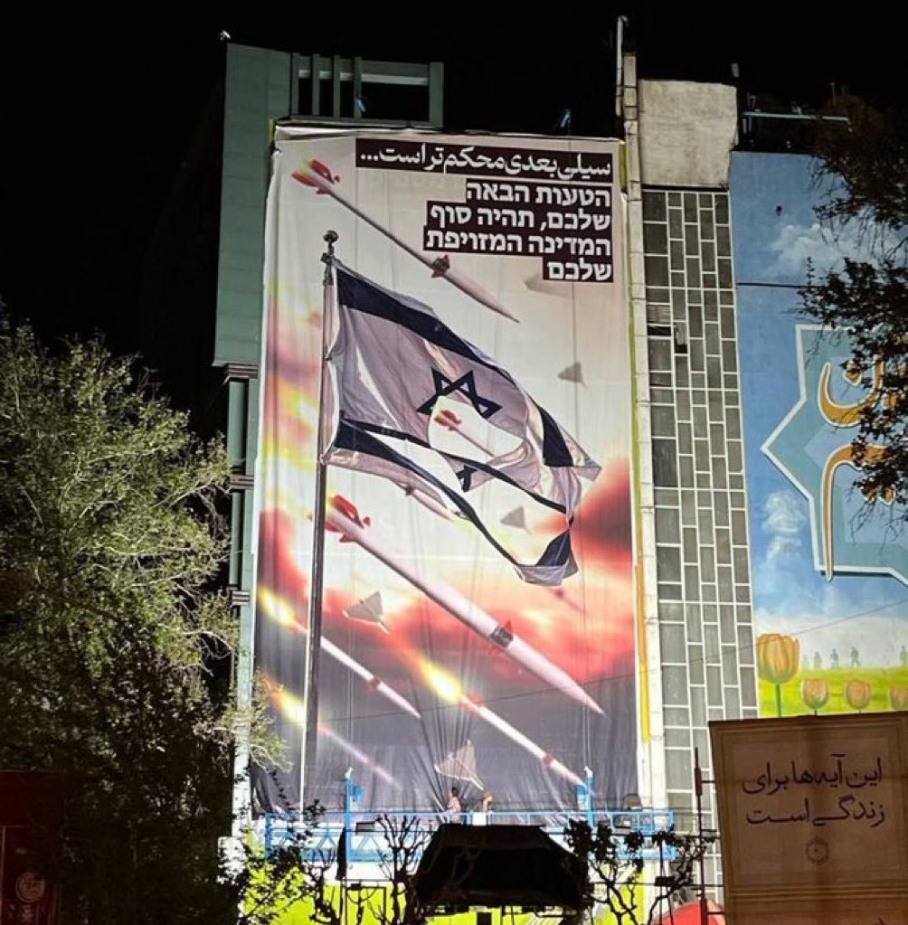 🚨🇮🇷🇮🇱 IRAN: 'THE NEXT SLAP WILL BE STRONGER' A new government-funded billboard in Palestine Square in Tehran was unveiled tonight after IRAN launched hundreds of drones, missiles, and rockets at Israel with hebrew text.