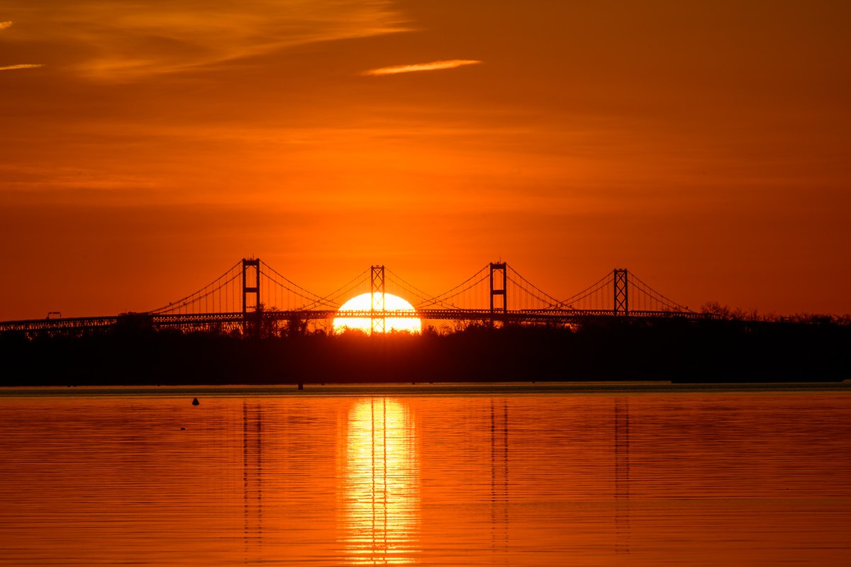 Nature's masterpiece: The sun gracefully emerges behind the majestic Chesapeake Bay Bridge, painting the morning sky with vibrant hues of orange and gold. #MDwx @capitalweather