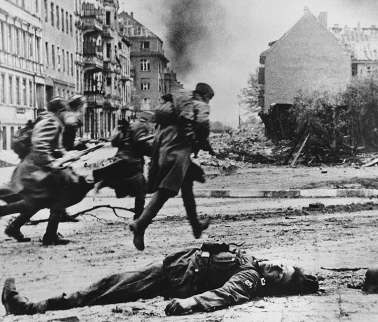 Galip ve mağlup: Berlin Muharebesi sırasında ölü bir Alman çavuşunun yanından koşarak ilerleyen Sovyet piyadeleri – Nisan 1945. 📸: Ivan Shagin
