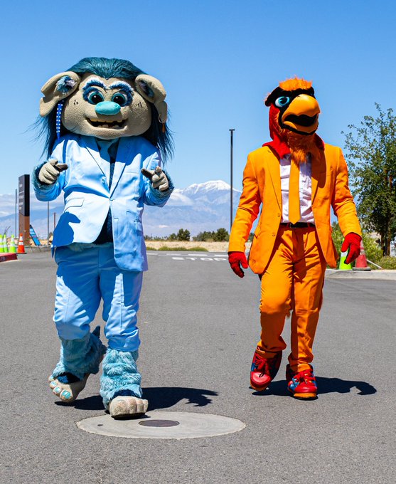 Fuego & Buoy walking while wearing an orange and light blue suit.