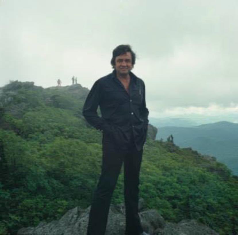 1974- Johnny Cash on a rock outcropping near the Mile High Swinging Bridge at Grandfather Mountain in Avery County, North Carolina. Photo was taken when Johnny and June Carter Cash were performers at the June 1974 'Singing on the Mountain' gospel music festival at Grandfather…