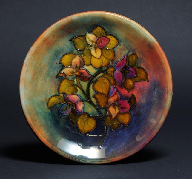 #MoorcroftMonday 'Bougainvillea' Plate by Walter Moorcroft The design is the 'Bougainvillea' floral design in greens, browns and reds. This design was introduced in the early 1950s and was used with the flambe glaze as well as having naturalistic colours. cannon-hall.com/collections
