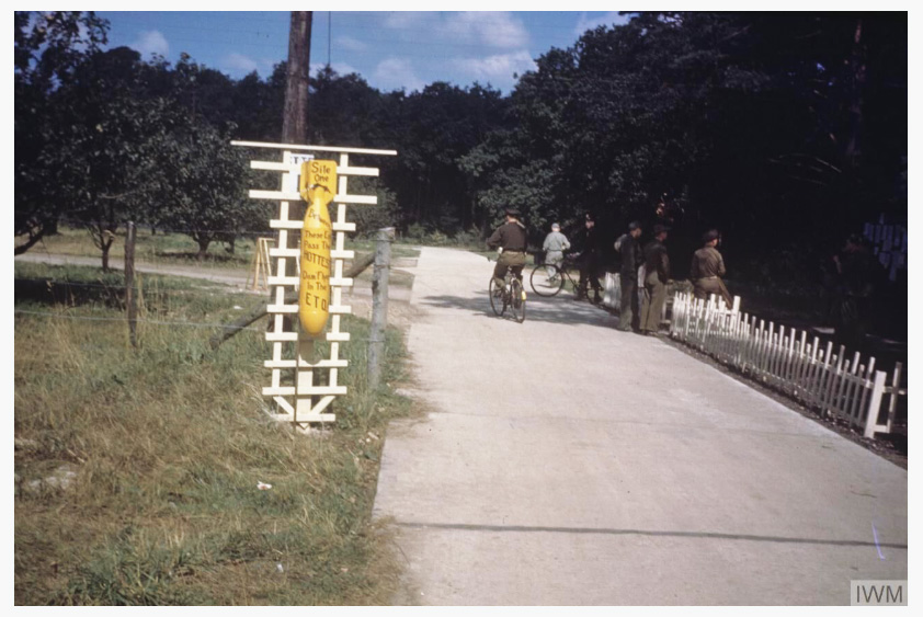 The front gate of the USAAF 467th Bomb Group base at Rackheath Airfield, Norfolk. © IWM FRE 6744 The bomb is graffitied with: 'Sile One, Between, These Eggs Pass The Hottest Damn Flyers In The ETO'