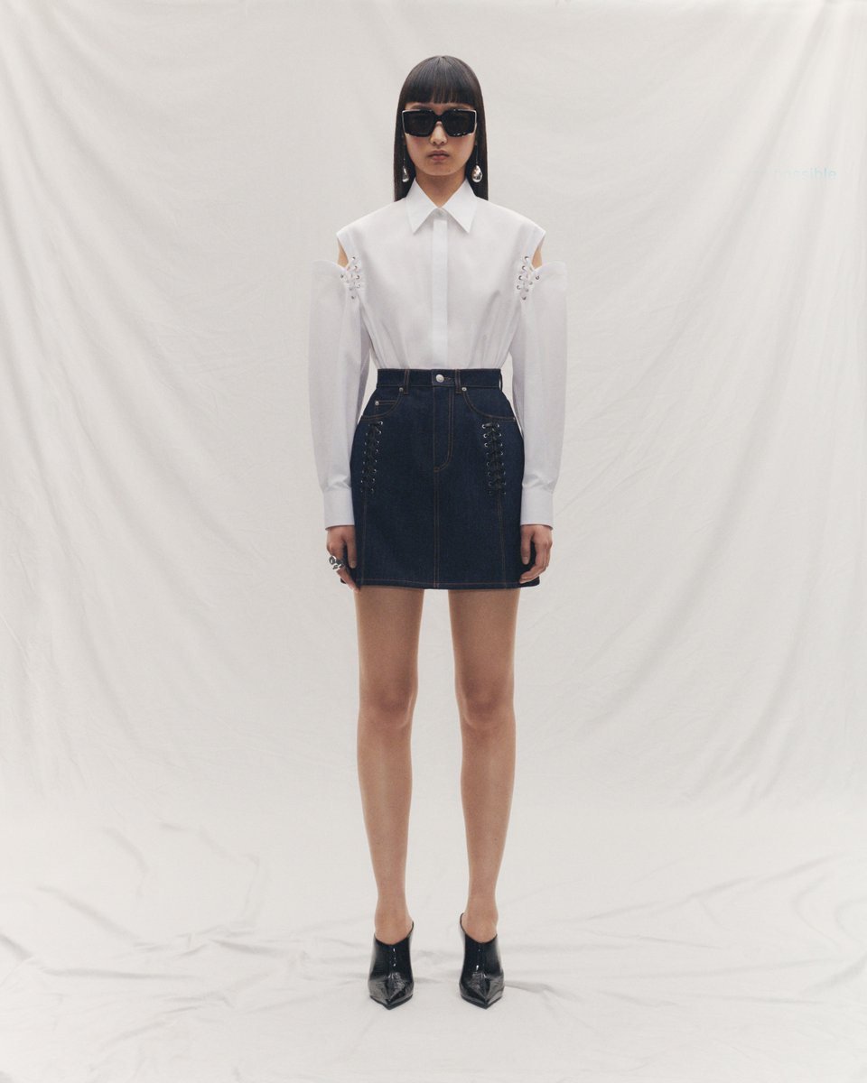 A white cotton poplin shirt and indigo denim skirt, both with slashed and lace detailing. Worn with the Grip sunglasses and silver pearl Stick earrings. Discover the #McQueenSS24 collection: on.alexandermcqueen.com/SS24_TW