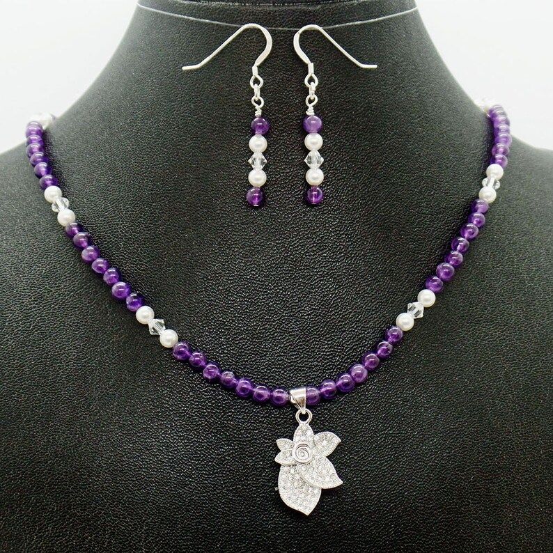 Handmade in the USA, this Amethyst Pearl Pave Crystal Flower Necklace Earrings Set from RivendellRocksSedona is a stunning piece of natural stone jewelry. Elevate your style with this unique small business find. #HandmadeJewelry #NaturalStone  buff.ly/3RmW39n