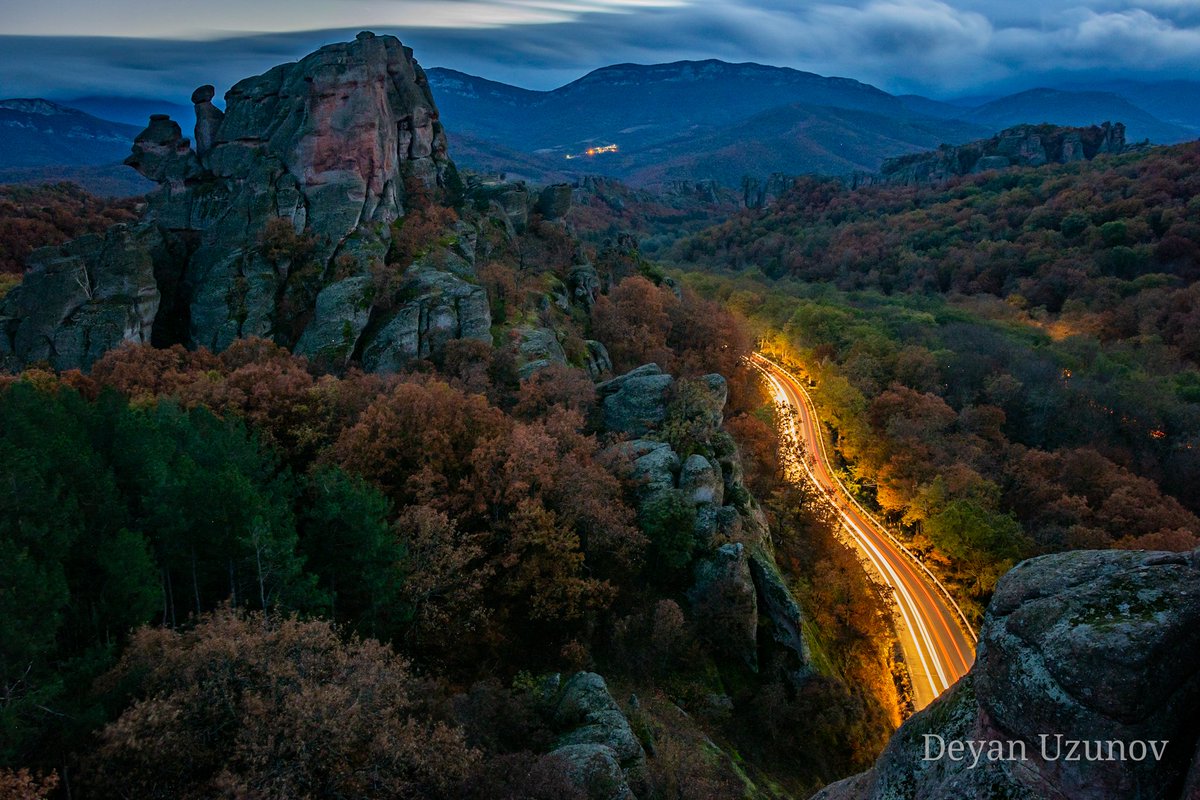 Light Trails Amidst Belograchik Rocks' Twilight As the sun gracefully dips below the horizon, casting its final golden hues on the jagged silhouettes of Belograchik Rocks, the world transforms. Here, amidst this ancient wonder, a mesmerizing dance of light and shadow begins.