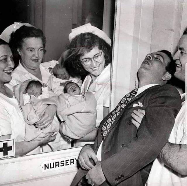 Nurses show triplets to the father who passes out with excitement. Photo from 1946, when ultrasound did not exist