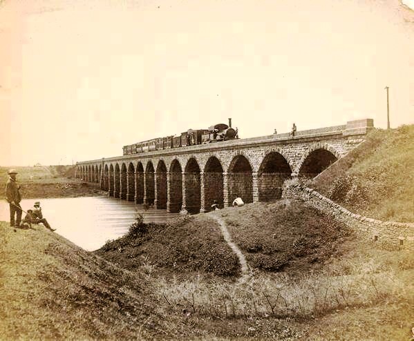GujaratHistory's tweet photo. Today is the 172nd birthday of the Indian Railway. 172 years old photo of India's first train on the bridge over Thane Creek. It was started between Mumbai and Thane on 16-4-1853. 
#NationalRailwayDay
https://t.co/PyQCR6l1eL