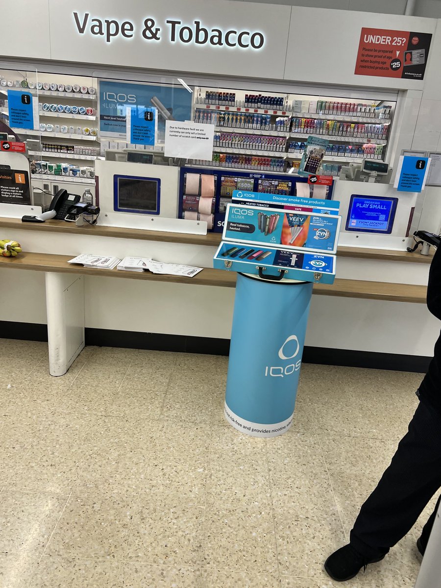 iqos advertising- with a person with an iqos tag selling- in a UK supermarket