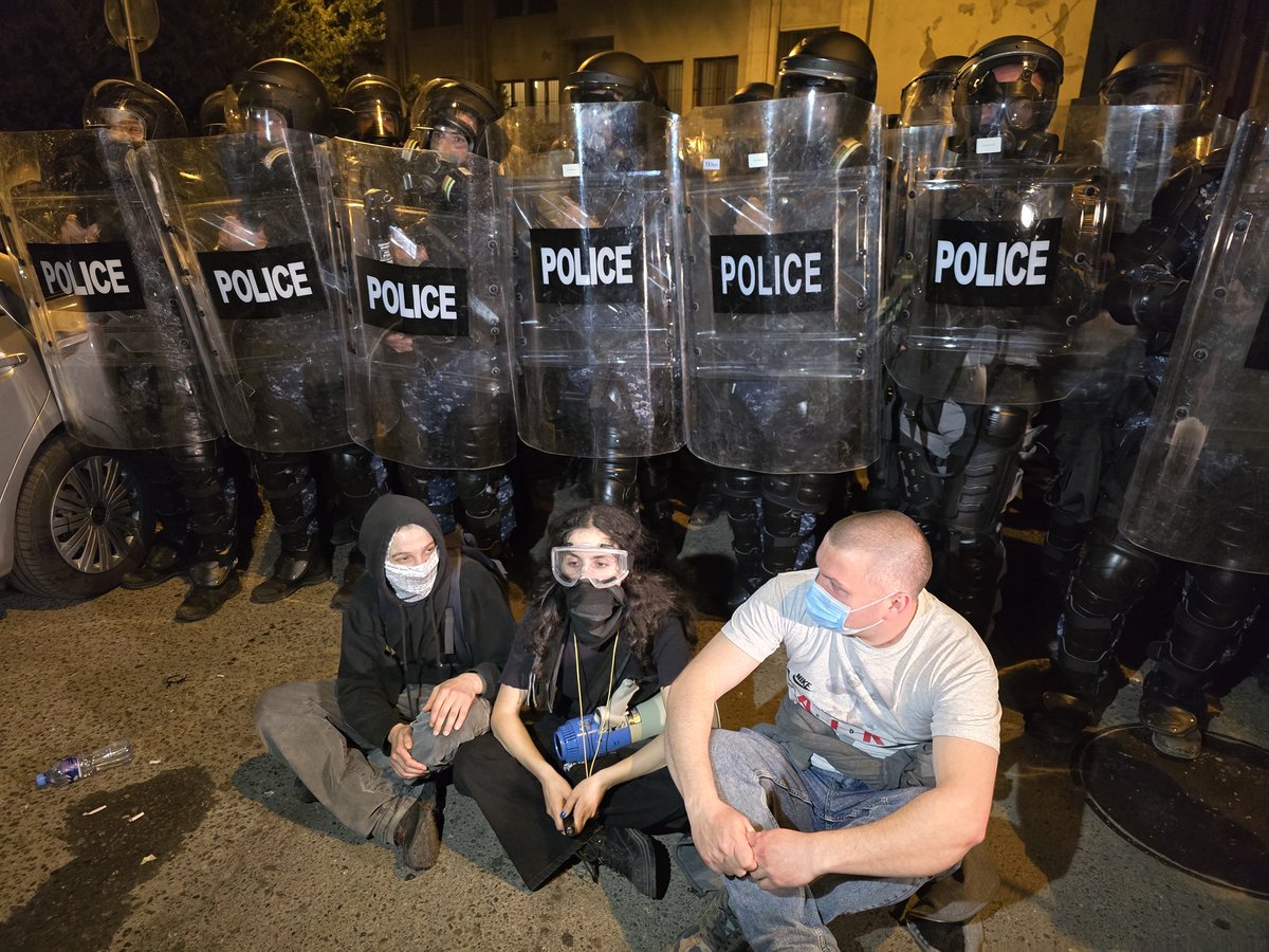 People sat in front of riot police and sing